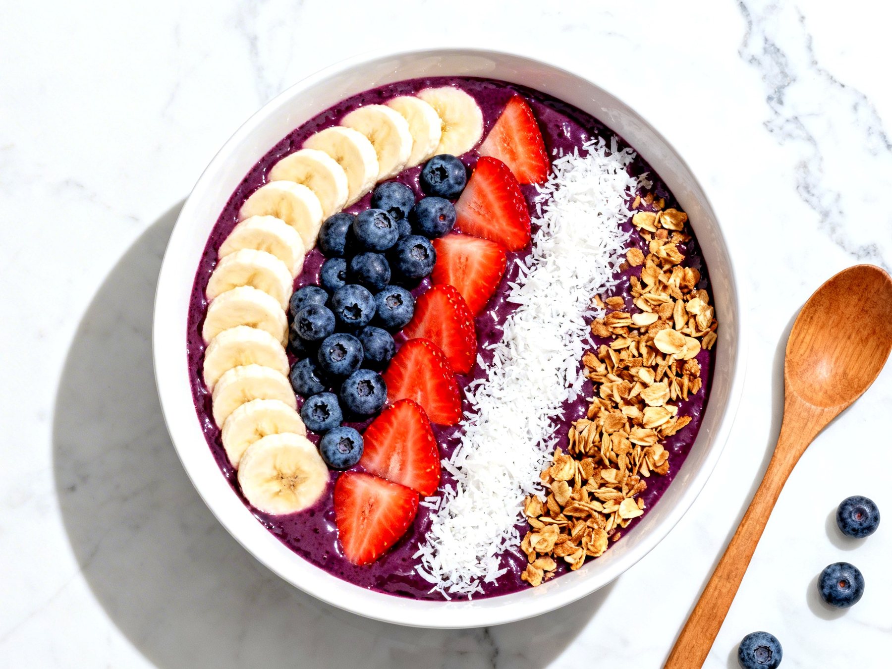 Tigela de açaí cremoso com banana, morango, mirtilo, coco e granola
